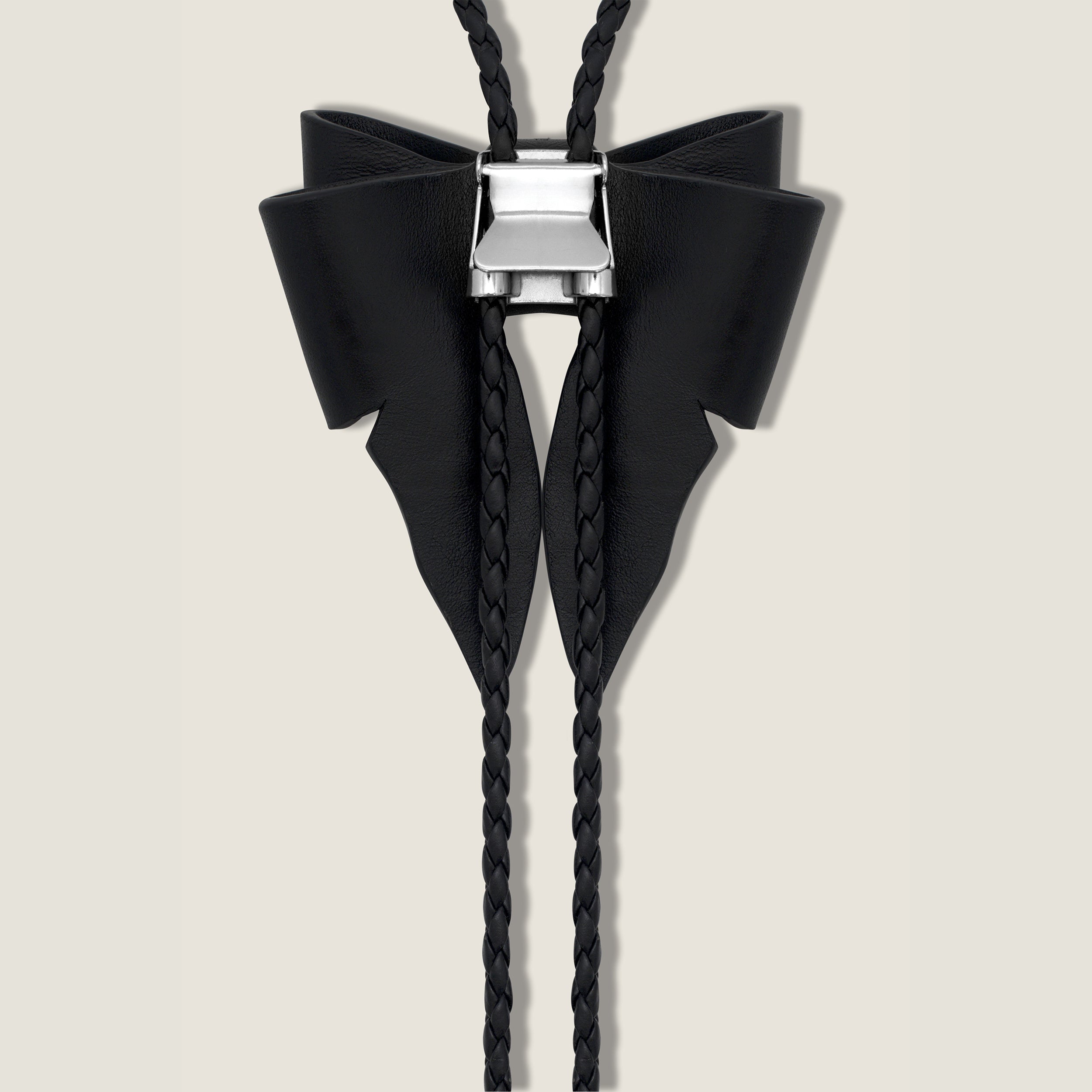 Black bow-shaped bolo tie on a beige background