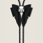 Black bow-shaped bolo tie on a beige background