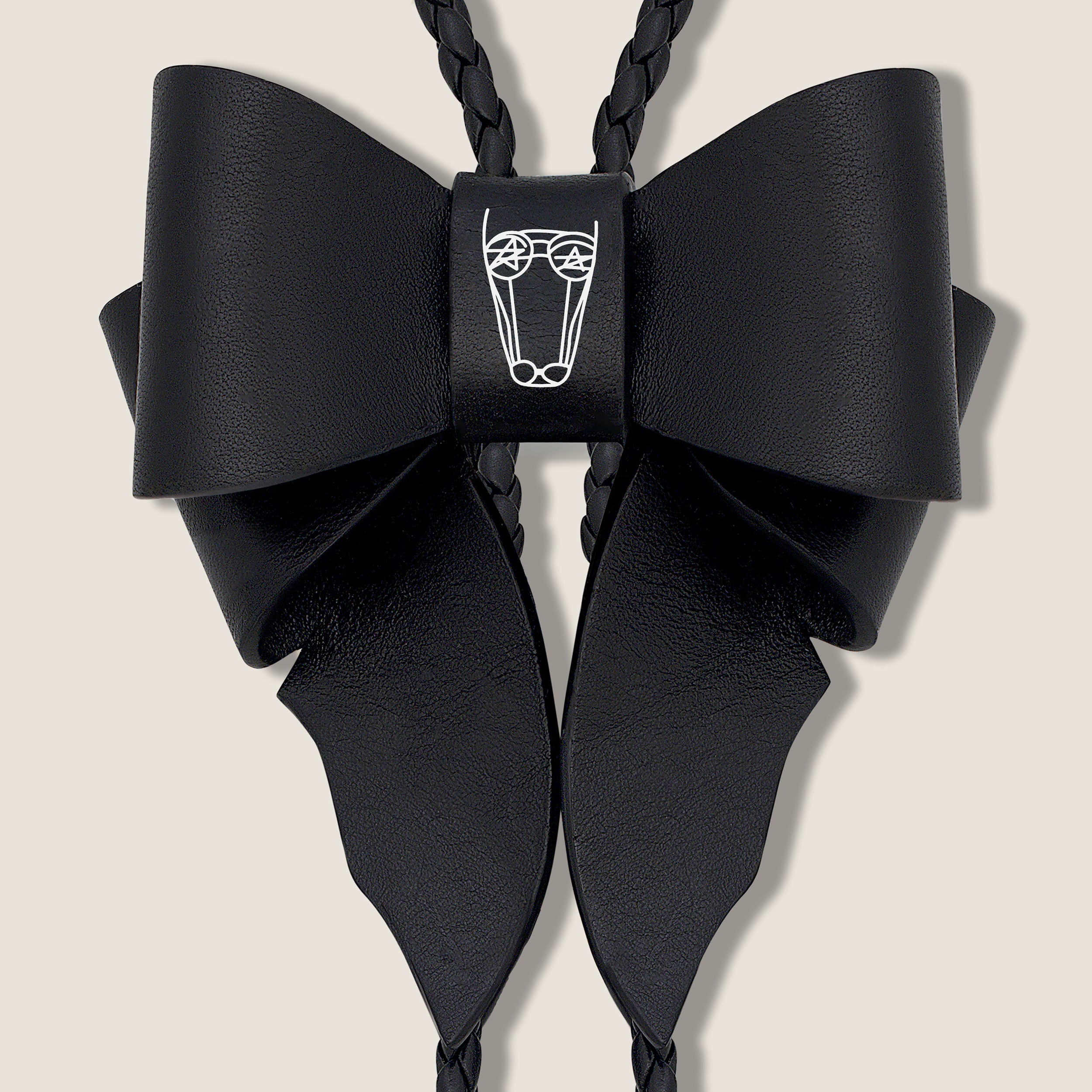 Black Leather Bow with Central Brand Logo on Beige Background
