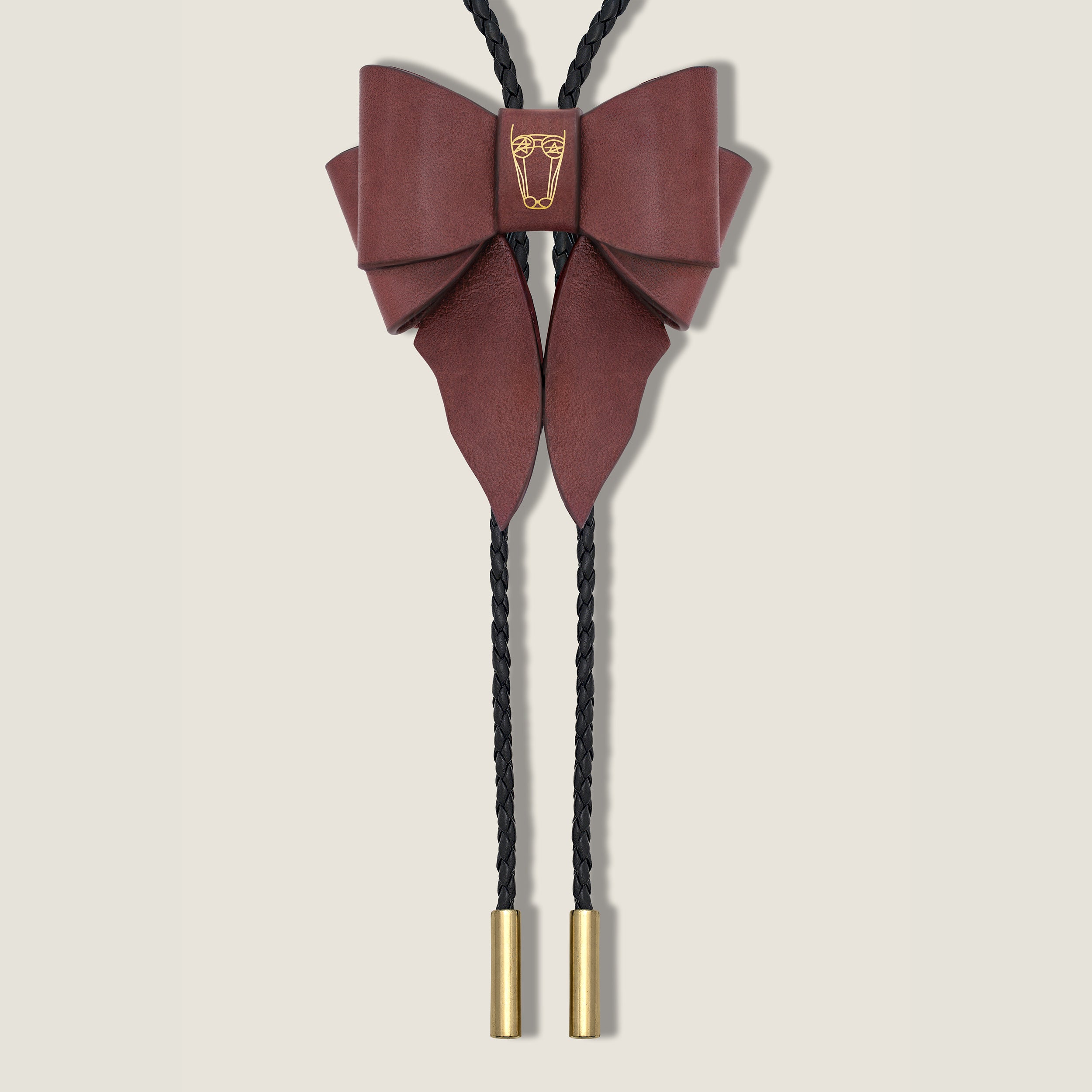 Maroon bow-shaped bolo tie with gold accents on a beige background