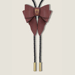 Maroon bow-shaped bolo tie with gold accents on a beige background