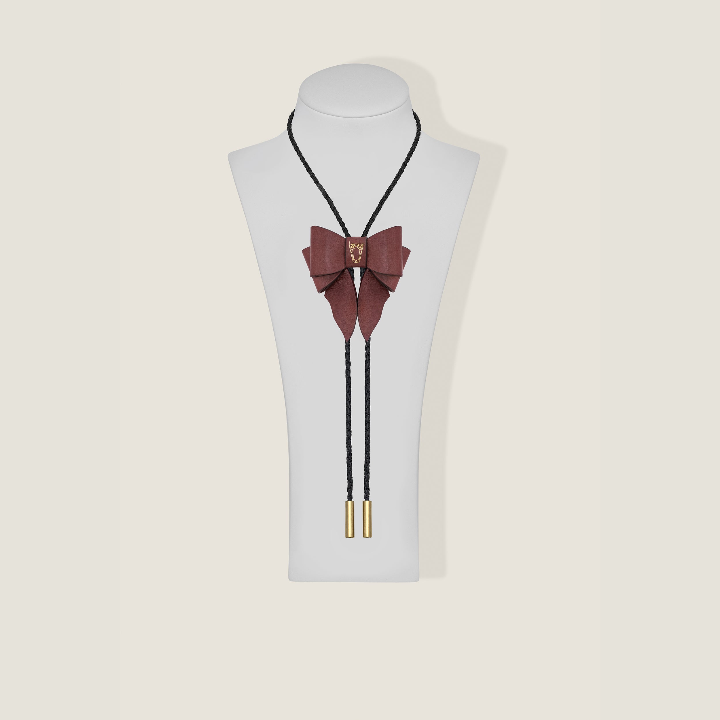 Burgundy bow tie necklace with gold accents on a mannequin bust against a beige background