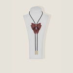 Burgundy bow tie necklace with gold accents on a mannequin bust against a beige background