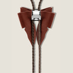 Brown bolo tie with braided leather cord on a beige background