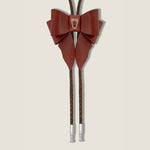 Brown leather bow tie with brown braided cord on a beige background