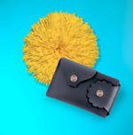 Marrs Makers Matte Black Leather Wallet. Bright turquoise background color with large sunflower in this product shot.